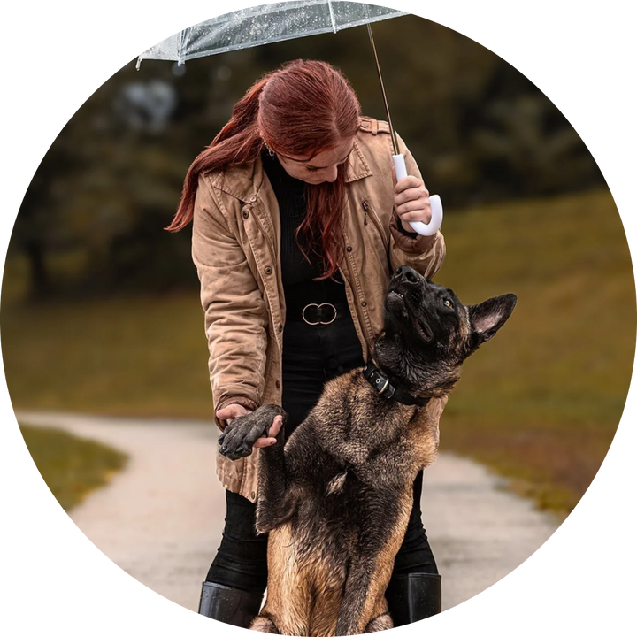 Aurore, d'UNIKDOG, sous un parapluie avec un malinois dressé contre elle